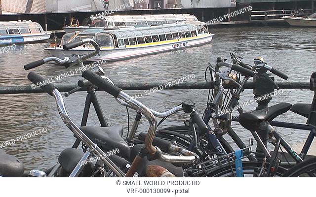 tourist canal boat behind bikes. Amsterdam. Netherlands