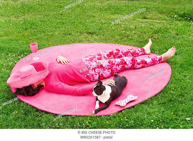 Woman in pink and dog relaxing outdoors on rug