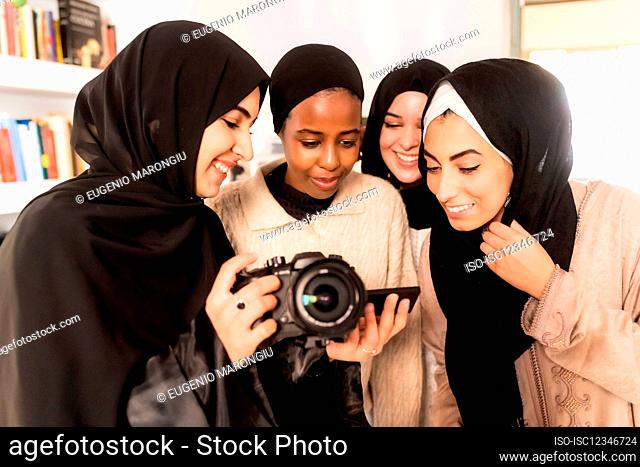 Four friends looking at photographs on camera