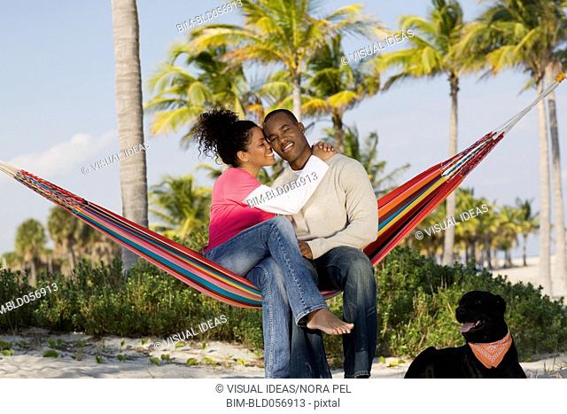 Hispanic couple hugging in hammock
