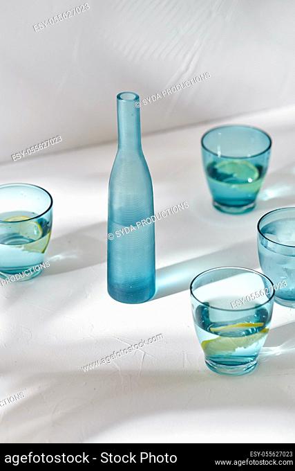 glasses with water and lemons on white background