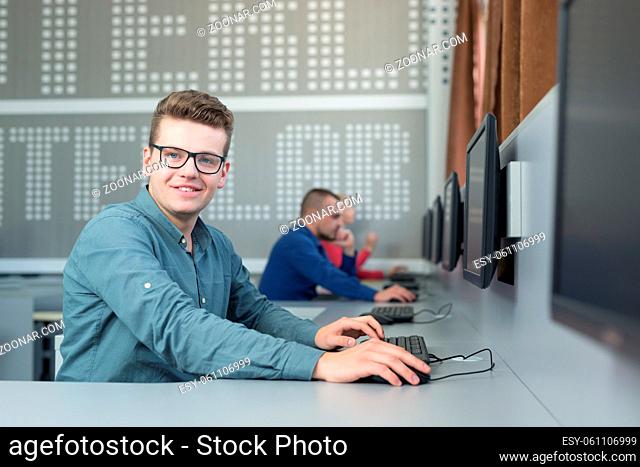 Casual businessman working with computer in office, looking at camera, smiling