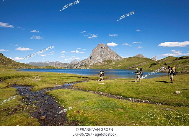 Hikers near lake Lac Gentau, Pic du Midi d'Ossau in background, Ossau Valley, French Pyrenees, Pyrenees-Atlantiques, Aquitaine, France