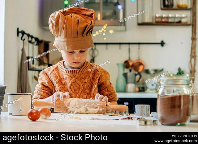 Boy preparing cookie dough with rolling pin at table