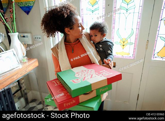 Mother with baby daughter receiving pizza delivery at front door