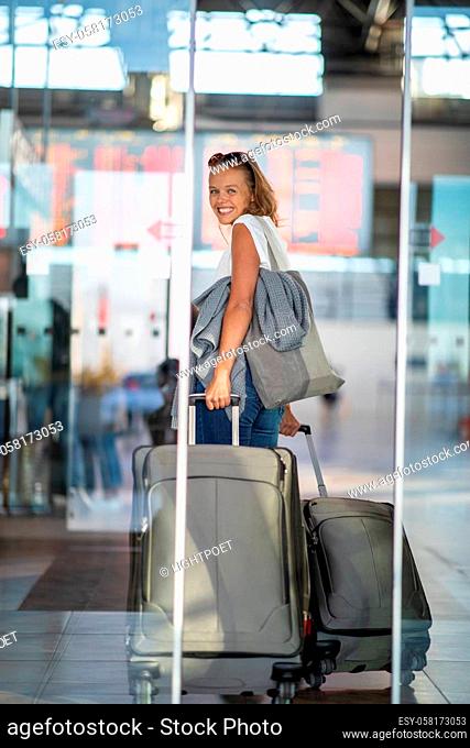 Young woman with her luggage at an international airport, before going through the check-in and the security check before her flight