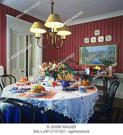 DINING ROOMS: Tone on tone red striped wallpaper, white crown molding and louvered folding doors, chandelier, round table in foreground
