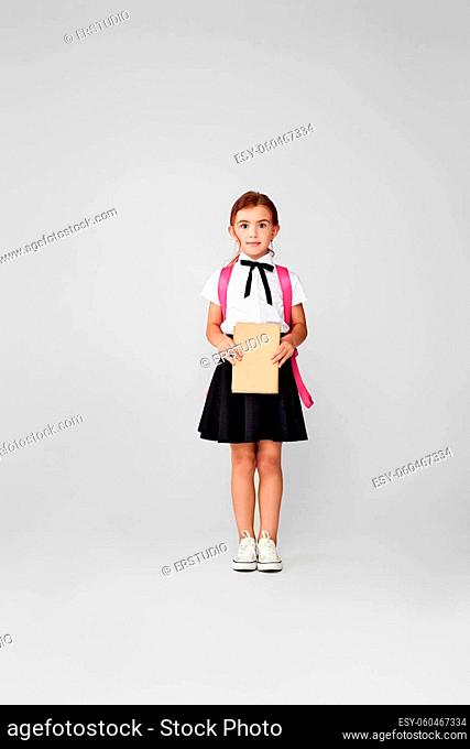 Back to school. attractive schoolgirl with pink backpack and book on blue background