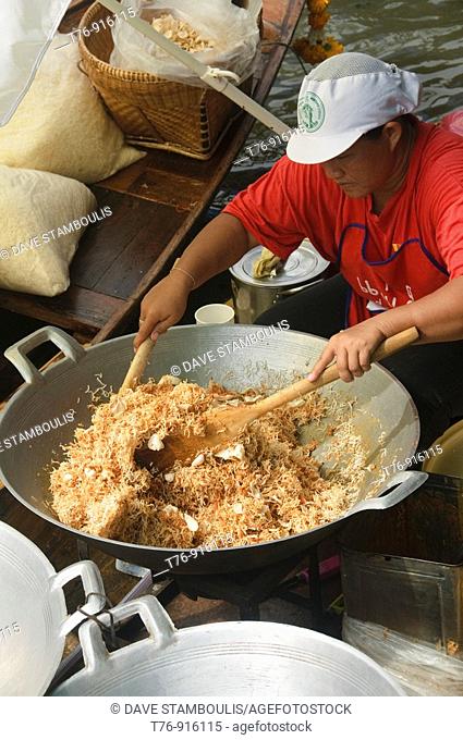 vendor making mee krob noodles at a floating market in Bangkok Thailand
