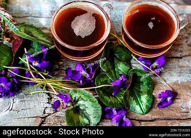 First spring flowers of violets and cup of coffee on the old wooden table