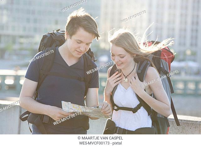 Germany, Berlin, Young couple traveling Berlin with backpacks, looking at map