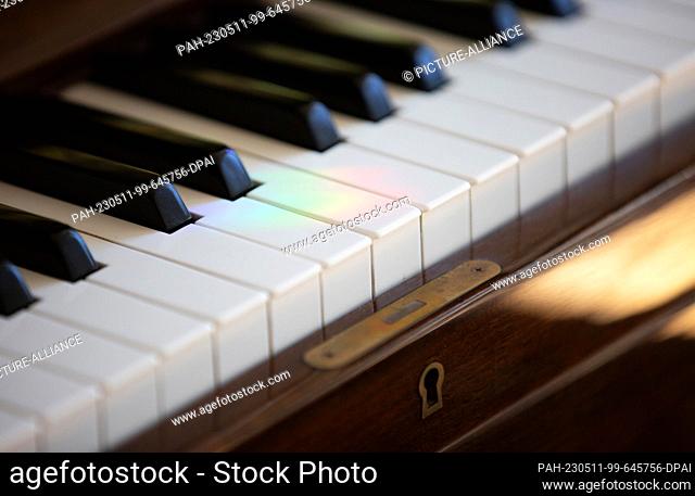 PRODUCTION - 30 April 2023, Berlin: On the keys of a piano in a living room, a light reflection in rainbow colors can be seen. Photo: Viola Lopes/dpa