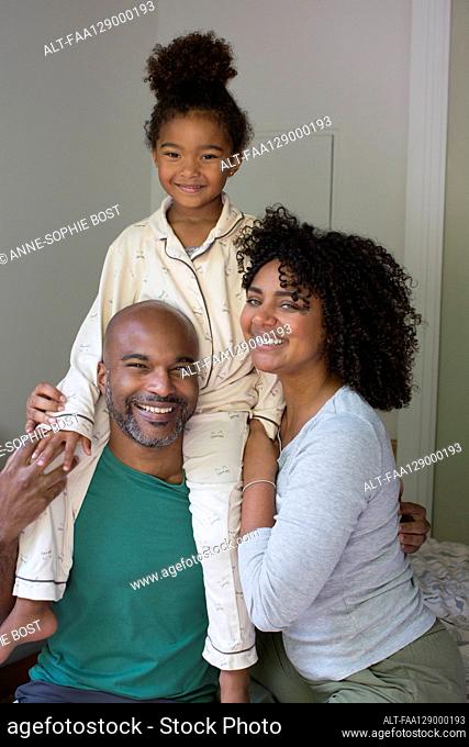 Smiling family sitting together on bed