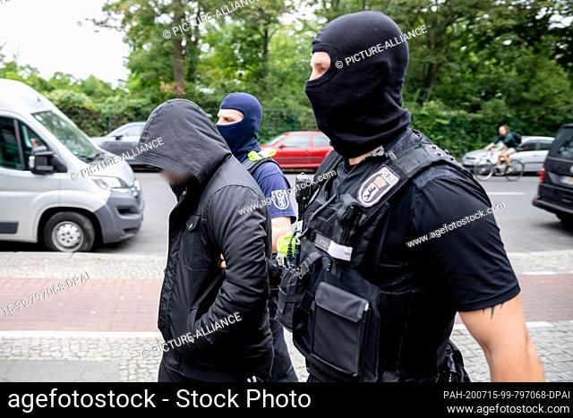 15 July 2020, Berlin: A man (l) is accompanied to a police vehicle by two policemen during a police operation in Berlin-Gesundbrunnen as part of a large-scale...