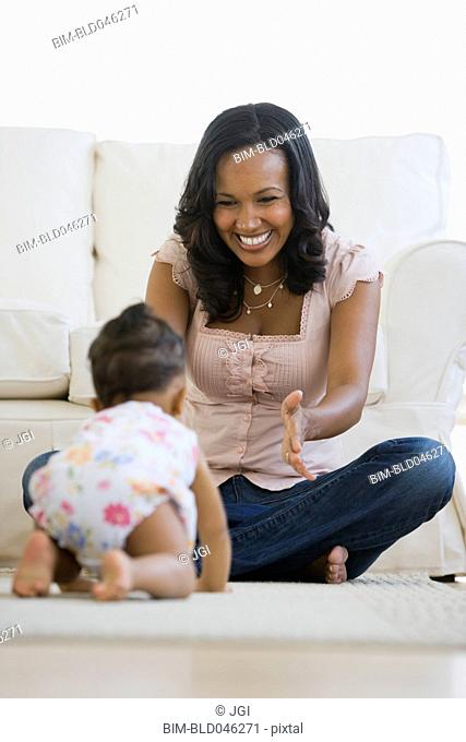 African American mother watching baby crawl