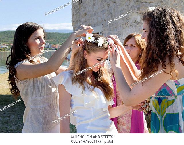 Women placing daisy crown on bride
