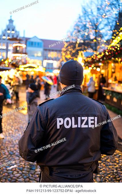 11 December 2019, Lower Saxony, Lüneburg: A policeman is standing at the Christmas market in front of the city hall. Photo: Philipp Schulze/dpa