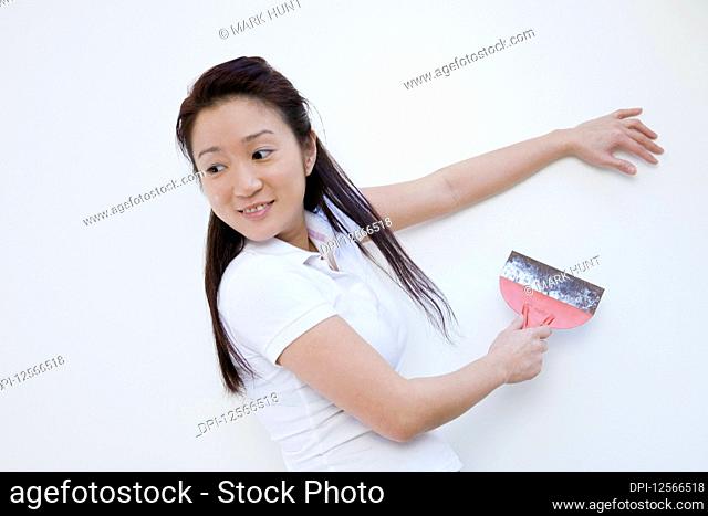 Side profile of a young woman scraping paint on wall