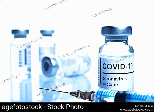 Glass vial with coronavirus vaccine label along with syringe closeup