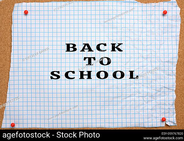 torn crumpled white sheet of paper in a cage pinned to a brown corkboard, lettering back to school