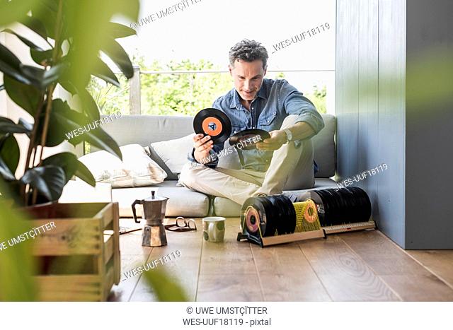 Mature man sitting at home, looking at vintage sigle recors