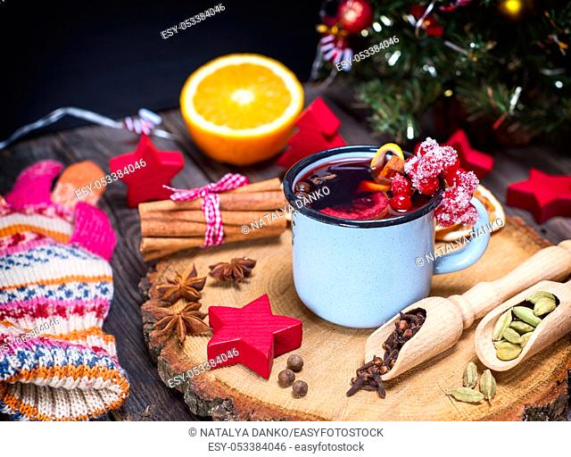 Mulled wine in an iron blue mug and drink ingredients among the Christmas decorations