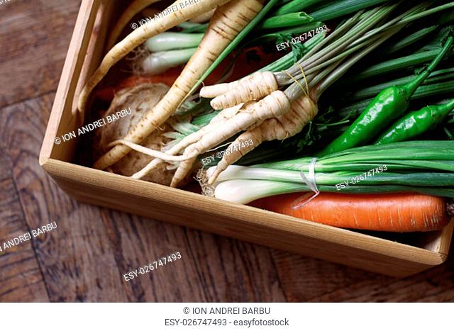 large wooden crate full of raw, freshly harvested vegetables. Carrots, parsnip, peppers