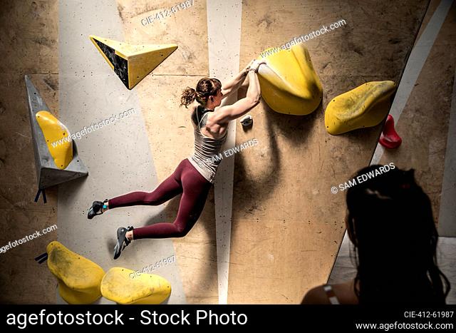 Woman hanging from rock climbing wall