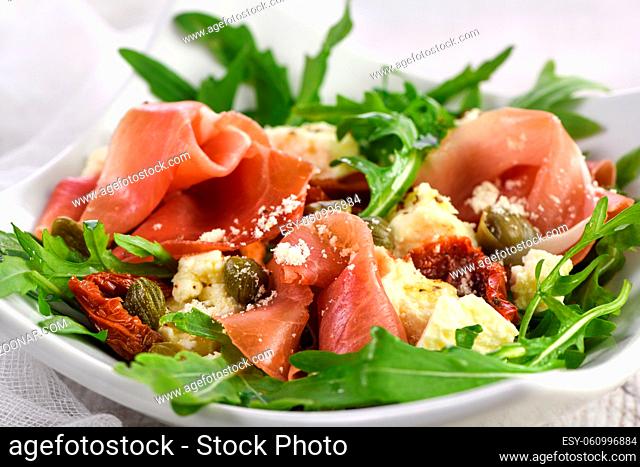 Arugula salad, prosciutto with sun-dried tomatoes, slices of mozzarella, capers, seasoned with olive butter and parmesan