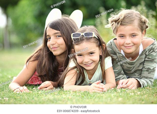 Three young girls lying on the grass