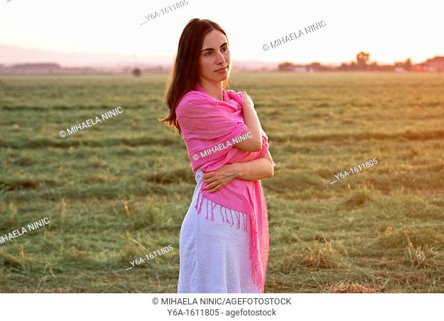 Portrait of a beautiful young woman wearing summer dress standing in field looking away