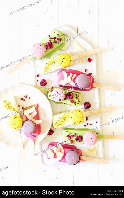 Vanilla cheesecake sticks with various chocolate glaze decorated with mini macarons, freese dried raspberries, coconut shaves and pistachio crumb