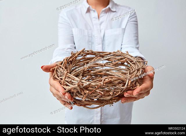 Girl gives a nest of twigs, isolated on a gray background. Easter
