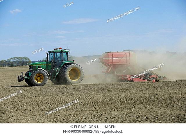 John Deere 7800 tractor with Horsch seed drill, drilling in dusty arable field, Sweden, April