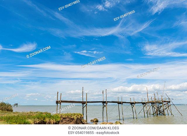 Medoc, France - August 19, 2014: Wooden jetty for fishing in the Gironde Medoc France with blue sky and white clouds