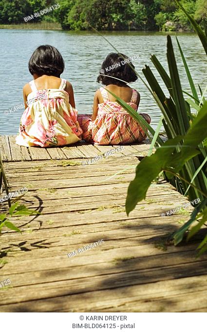 Indian girls sitting on dock over lake