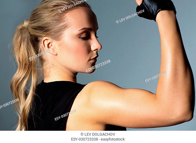 sport, fitness and people concept - close up of young woman posing and showing muscles in gym