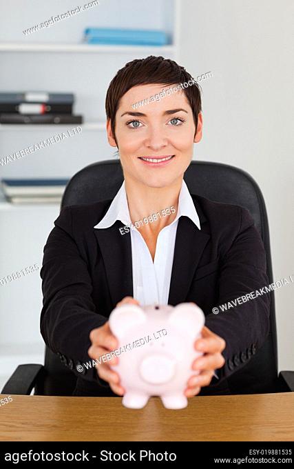 Portrait of a smilling office worker holding a piggybank
