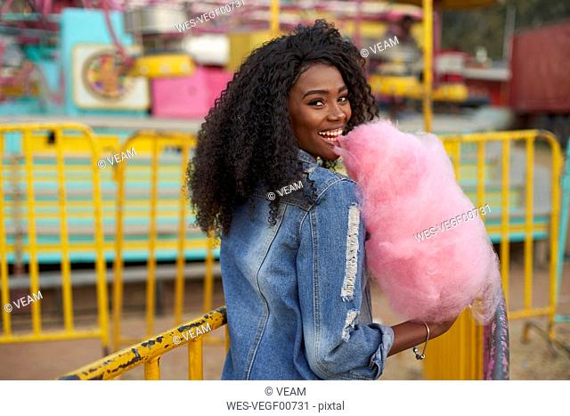 Portrait of happy young woman with pink candyfloss at fair