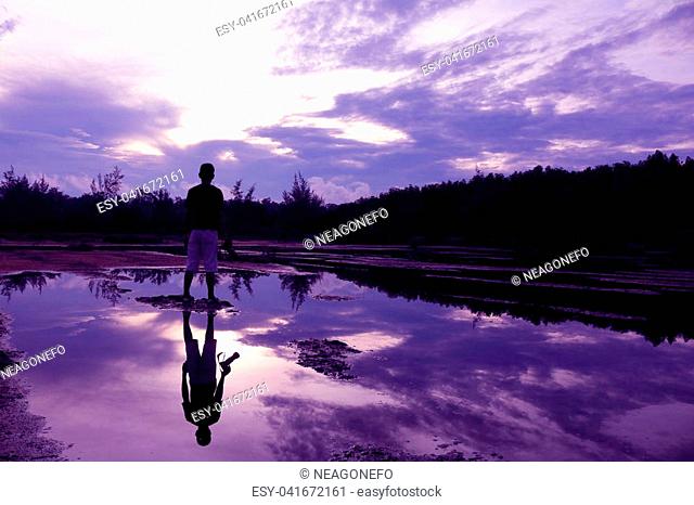 Mirror of purple sky in the morning reflection to the water with shadow of photographer in Thailand
