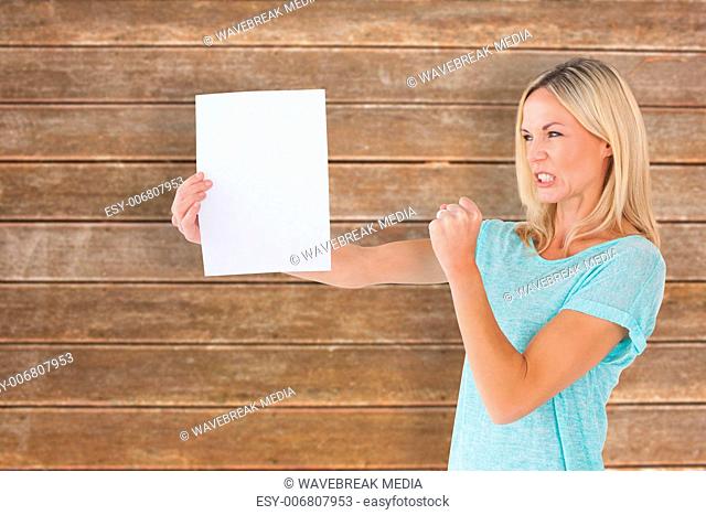 Composite image of angry woman holding piece of paper