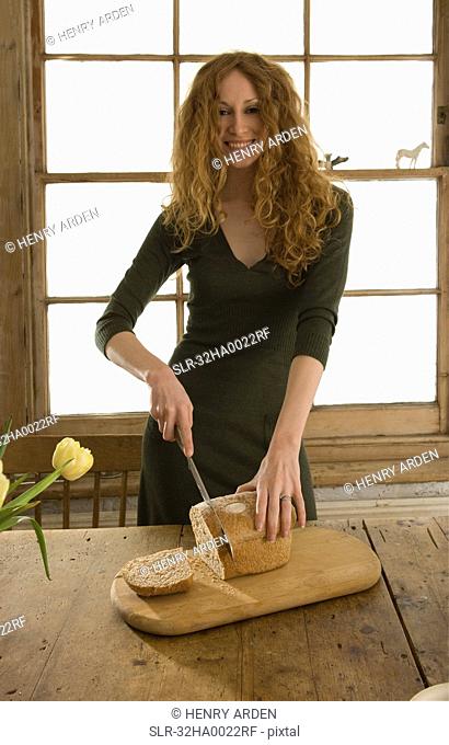 Woman slicing bread in kitchen