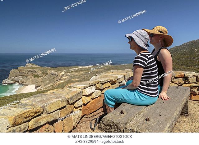 Two women sitting on a bench at cape of good hope enjoying the view over the ocean, Cape of good hope, Cape Town, South Africa
