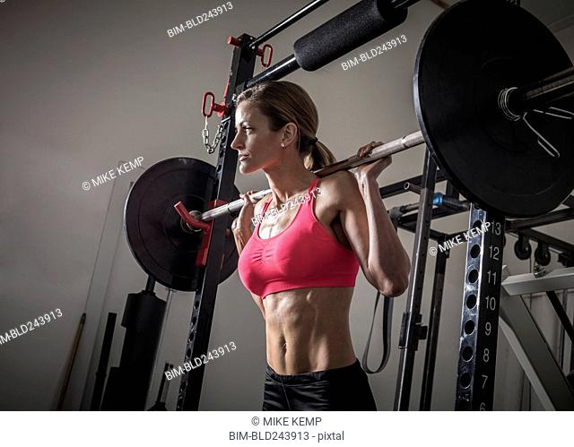 Woman lifting barbell in gymnasium