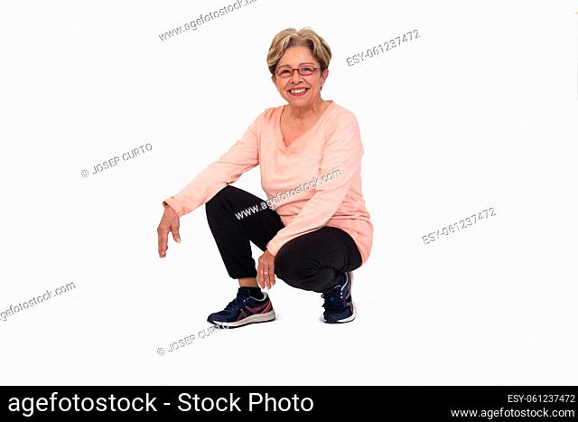 front view of a happy senior woman squatting on white backgrond