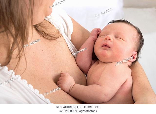 Baby 2 weeks old in mother's arms, asleep after being breast feeded