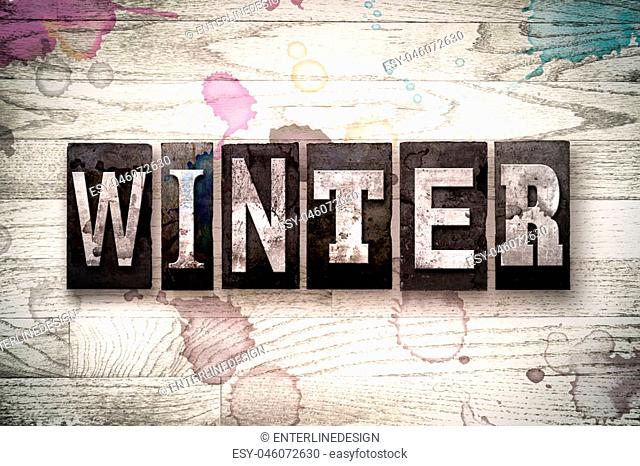 The word ""WINTER"" written in vintage, dirty metal letterpress type on a whitewashed wooden background with ink and paint stains