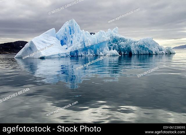 Bluish iceberg in a calm sea and a cloudy day
