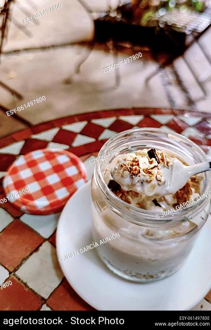 Spoonful of yogurt with muesli from glass jar. Mediterranean style background