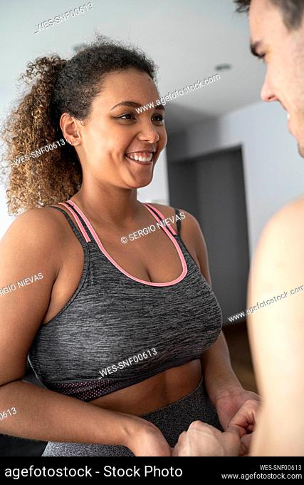 Woman wearing sports clothing looking at man while standing at home